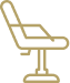 A close-up of a salon chair with a large mirror, hair styling tools, and a plant on a counter in a modern, well-lit salon.